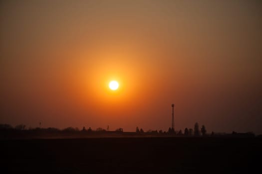 Red sunset over the field. Beautiful sunset in nature. Rural nature at sunset. Red sunset landscape