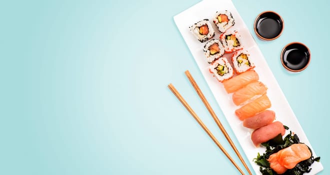 Sushi rolls set with salmon and tuna fish on light blue background from above. Top view of traditional japanese cuisine. Asian food restaurant menu modern design.