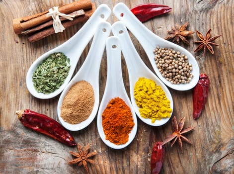 Top view on mixed dry colorful spices on wooden rustic table. Indian food and various oriental cooking ingredients background.