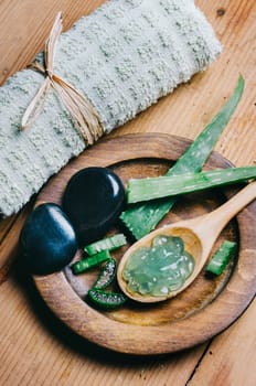 Top view of aloe vera spa and wellness cosmetic product for skin and beauty care. Herbal natural aromatherapy and zen massage stones on vintage wooden table. Asian alternative medicine treatment.
