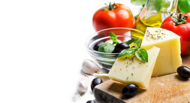 Goat cheese, olives, olive oil, tomato, garlic, basil and spices on wooden cutting board isolated on white background. Food ingredients for italian pizza recipe. Mediterranean cuisine with dairy product and organic vegetable and herbs.