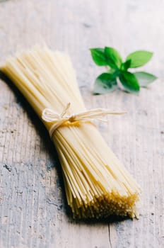 Italian raw pasta on rustic wooden table. Traditional long spaghetti dry.