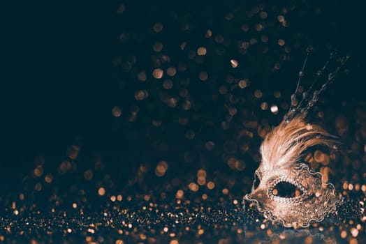 Luxury venetian mask on dark godlen bokeh background. New year and christmas party celebration design banner. Carnival masquerade fantasy costume ball.