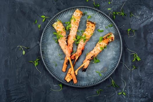 Classic shrimp or langoustines barbecue with herbs grilled on wooden sticks. Top view