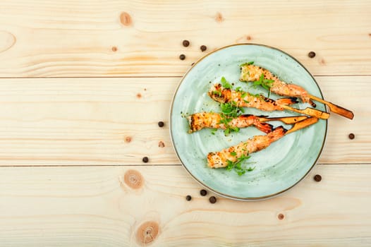 Classic shrimp or langoustines barbecue with herbs grilled on wooden sticks. Top view