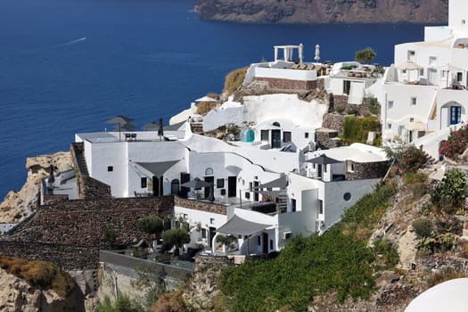Oia, Santorini, Greece - July 3, 2021: Whitewashed houses with terraces and pools and a beautiful view in Oia on Santorini island, Greece