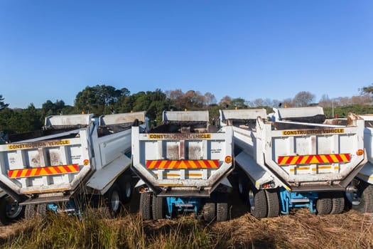 Construction Truck vehicles parked roadside  used for  new asphalt tar surfacing maintenance on car highways.