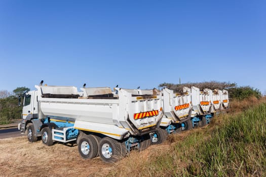 Construction Truck vehicles parked roadside used for new asphalt tar surfacing maintenance on car highways.