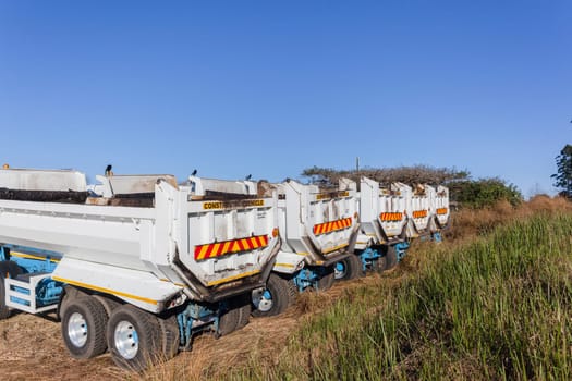 Construction Truck vehicles parked roadside used for new asphalt tar surfacing maintenance on car highways.
