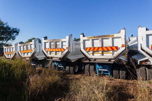 Construction Truck vehicles parked roadside used for new asphalt tar surfacing maintenance on car highways.