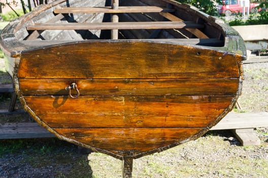 one old rowboat made of wood it s on land in the harbour