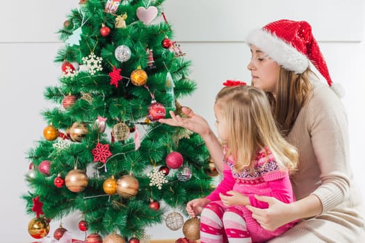 Christmas Happy Family mother and her two little daughters sitting on the floor and open Holidays Gift.