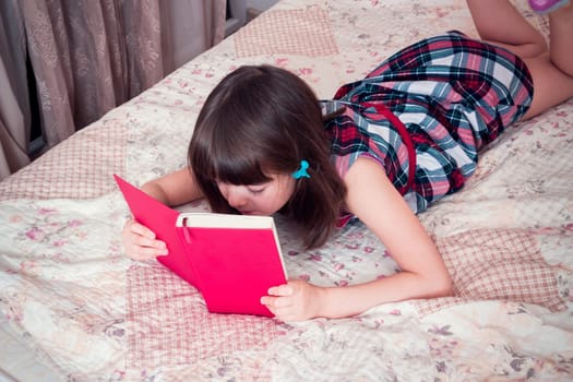 Little girl reading a book at home