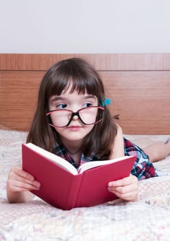 Little girl reading a book at home