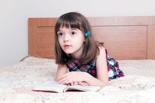 Little girl reading a book at home