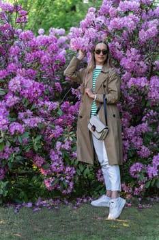 Long-haired woman in sunglasses vohle of a lushly blooming rhododendron bush
