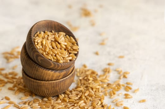 Wooden bowls of raw dry rye grain on white table close up. Healthy alternative low gluten seeds. Protein source for vegan and vegetarian diet.