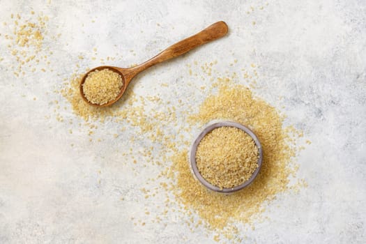 Wooden scoop and bowl with Dry uncooked bulgur wheat grain top view. Vegetarian and Vegan, Mediterranean and Middle Eastern cuisine. Healthy food