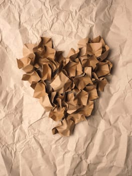 Heart shape made from recycled paper packaging material on a crushed recycled paper background