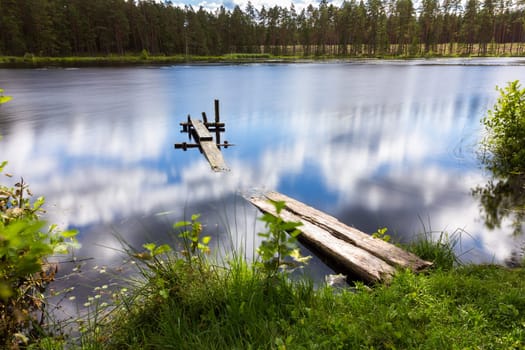 A small mesa lake with a boardwalk. Reflection of clouds in it.