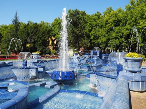 Subotica, Serbia September 12, 2021. Blue fountain in the square next to the Town Hall. Blue ceramic parts with monograms. A working fountain with splashing water. Summer sunny day by the blue water.