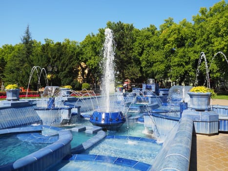 Subotica, Serbia September 12, 2021. Blue fountain in the square next to the Town Hall. Blue ceramic parts with monograms. A working fountain with splashing water. Summer sunny day by the blue water.