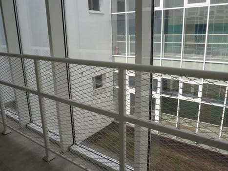 New white frames and windows. Metal fence for the safety of schoolchildren. New modern school. View from the window to the opposite wall and windows. Security systems. Internal office interior