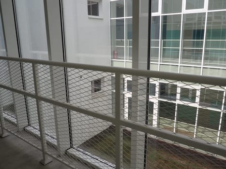 New white frames and windows. Metal fence for the safety of schoolchildren. New modern school. View from the window to the opposite wall and windows. Security systems. Internal office interior