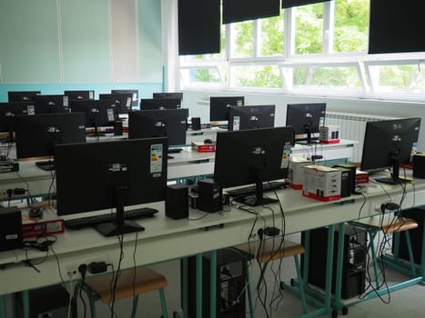 Sremska Mitrovica, Serbia, May 15, 2021 Group of computer neatly placed in a computer lab. Computers, monitors, wires in the modern classroom of the new school. School desks for pupils and students.