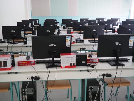 Sremska Mitrovica, Serbia, May 15, 2021 Group of computer neatly placed in a computer lab. Computers, monitors, wires in the modern classroom of the new school. School desks for pupils and students.