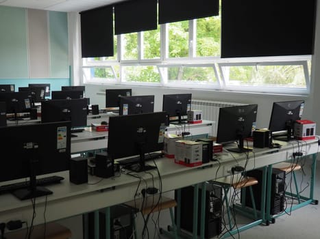 Sremska Mitrovica, Serbia, May 15, 2021 Group of computer neatly placed in a computer lab. Computers, monitors, wires in the modern classroom of the new school. School desks for pupils and students.