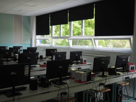 Sremska Mitrovica, Serbia, May 15, 2021 Group of computer neatly placed in a computer lab. Computers, monitors, wires in the modern classroom of the new school. School desks for pupils and students.