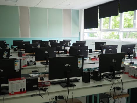 Sremska Mitrovica, Serbia, May 15, 2021 Group of computer neatly placed in a computer lab. Computers, monitors, wires in the modern classroom of the new school. School desks for pupils and students.