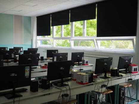Sremska Mitrovica, Serbia, May 15, 2021 Group of computer neatly placed in a computer lab. Computers, monitors, wires in the modern classroom of the new school. School desks for pupils and students.