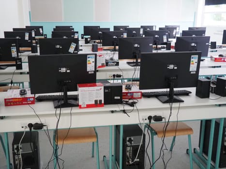 Sremska Mitrovica, Serbia, May 15, 2021 Group of computer neatly placed in a computer lab. Computers, monitors, wires in the modern classroom of the new school. School desks for pupils and students.
