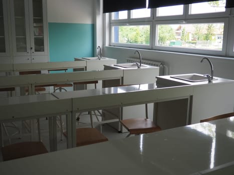 Chemistry room in a modern new school. Beautiful white furniture with sinks and washbasins. Large windows with blackout curtains or blinds. Empty school classroom. Furniture and school equipment.