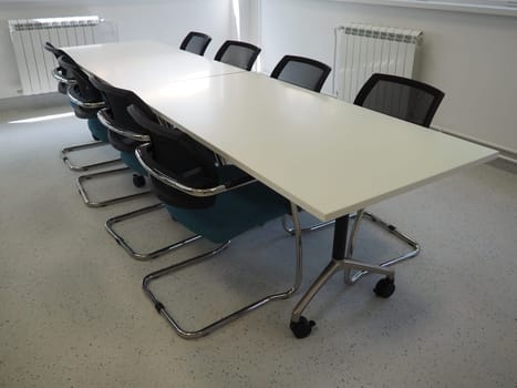 table and chairs in the meeting room or in the auditorium. Library, office, or premises in an official institution or bank. There is no one at the table. White, black and gray paints in the interior.