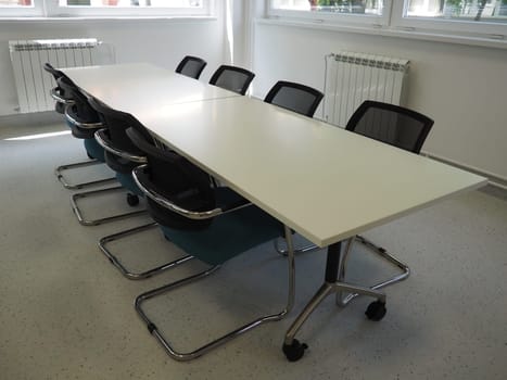 table and chairs in the meeting room or in the auditorium. Library, office, or premises in an official institution or bank. There is no one at the table. White, black and gray paints in the interior.