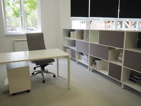 table and chairs in the meeting room in the office, in the classroom or in the library hall. White, black and gray paints in the interior. Black blinds for darkening the room. Modern interior design.