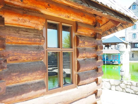Stanisici, Bijelina, Bosnia and Herzegovina, April 25, 2021. Fashionable log house close-up. Glass window with wooden frame. The wall of a wooden building with a canopy from the roof. Ethno-village.