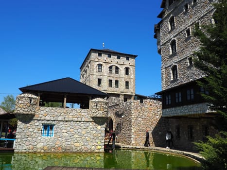 Stanisici, Bijelina, Republika Srpska, Bosnia and Herzegovina April 25 2021 Ethno village, tourism and attractions. Stone and wooden buildings of the hotel. People visit restaurant, traditional houses