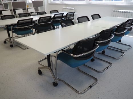 table and chairs in the meeting room or in the auditorium. Library, office, or premises in an official institution or bank. There is no one at the table. White, black and gray paints in the interior.