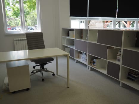 table and chairs in the meeting room in the office, in the classroom or in the library hall. White, black and gray paints in the interior. Black blinds for darkening the room. Modern interior design.
