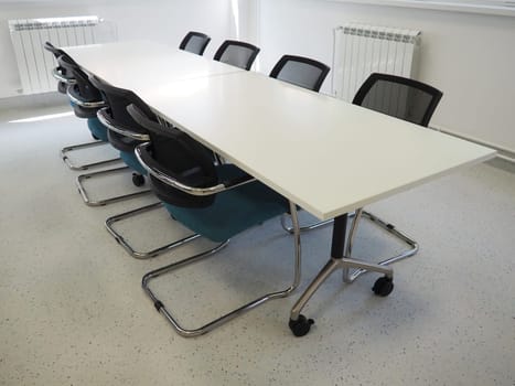 table and chairs in the meeting room or in the auditorium. Library, office, or premises in an official institution or bank. There is no one at the table. White, black and gray paints in the interior.