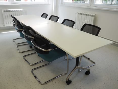 table and chairs in the meeting room or in the auditorium. Library, office, or premises in an official institution or bank. There is no one at the table. White, black and gray paints in the interior.
