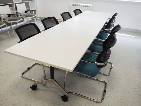table and chairs in the meeting room or in the auditorium. Library, office, or premises in an official institution or bank. There is no one at the table. White, black and gray paints in the interior.