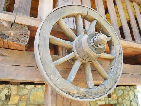 Wooden wheel from a cart. Decorative wheels for decorating lawns, exteriors and rustic interiors. A round homemade wheel hangs on the wall. Retro or vintage style. Life in the countryside.