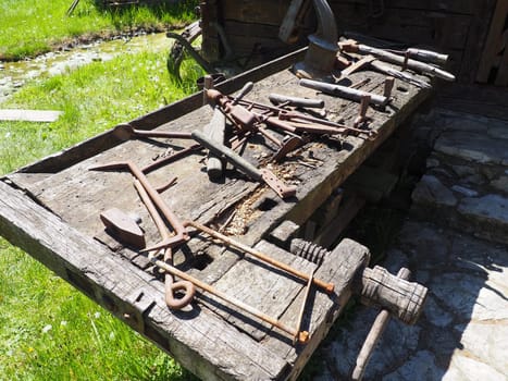vintage working tools on a wooden table. Wooden and metal tools for building and rural life. Hammer, bracket, saw, ax, drill, tongs, poker, spoon, wooden vice. Village life. Joinery and carpentry.