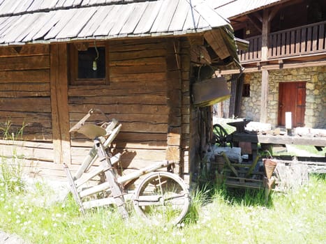 Stanisici, Bijelina, Bosnia and Herzegovina, 25 April 2021. Log village farmhouse. 19th century Bosnian mountain traditional dwelling. Restored ethno building. Antique wooden wheel from chariot.