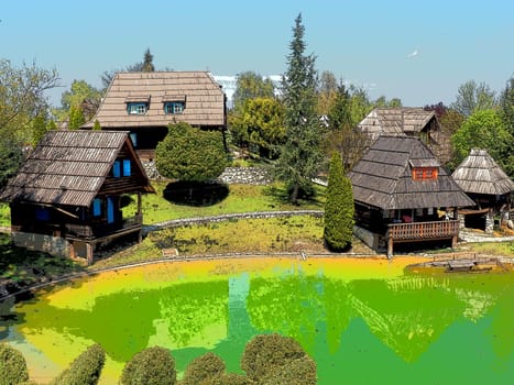 Stanisici, Bijelina, Bosnia and Herzegovina. April 25, 2021 Ethno-village, traditional village houses made of logs, Bosnian style of construction in the highlands. Lake with water. Wooden architecture